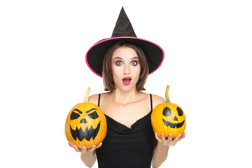 Happy young woman in black costume holding halloween pumpkins on white background