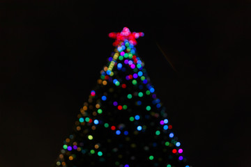 Christmas tree light on black background. blurry bokeh tree lights, Red star on the top of the head