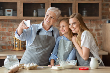 Female family taking selfie on cellphone while cooking together