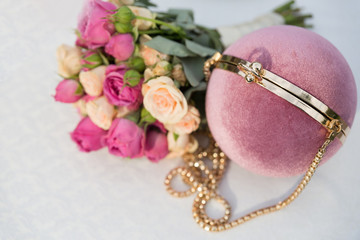 Round gently pink clutch and bridal bouquet of white and pink roses on a white background. The original women's handbag.