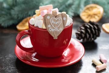 Festive Christmas composition with red cup of hot chocolate with marshmallows  on black vintage table with Christmas tree branches and decor. New Year and Christmas concept.