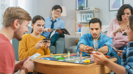 Diverse Group of Guys and Girls Playing in a Strategic Board Game with Cards and Dice. Cozy Living Room in a Daytime