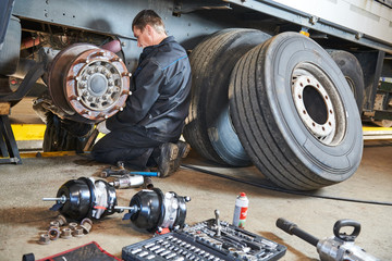 Truck repair service. Mechanic works with brakes in truck workshop - 292974804