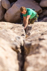 Man jamming his fist in a crack in the rock. Trad climbing in Joshua Tree. 