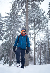 Smiling diverse couple holding Christmas presents while walking through a winter forest