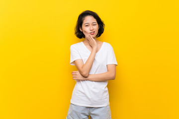Asian young woman over isolated yellow wall with toothache