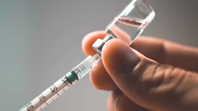 Doctor with medical syringe in hands, getting ready for injection
