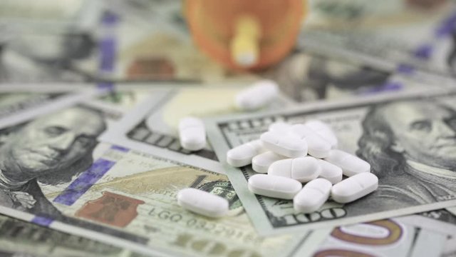 Prescription pills on background of one hundred dollar bills cash