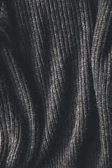 Fototapeta na wymiar Texture of a black knitted sweater closeup. dark knitted wool material background