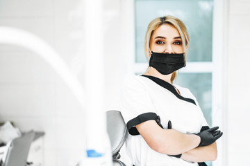 Pertrait photo of the female doctor in black mask and black gloves.