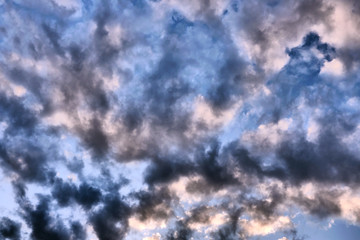 Big dark dramatic fluffy clouds in the blue sky on sunny light. Abstract nature background.
