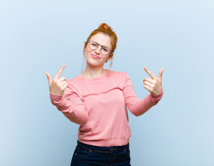 young red head pretty woman with a bad attitude looking proud and aggressive, pointing upwards or...