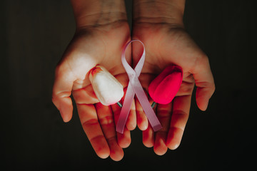 Caucasian Woman holding a pink ribbon and two tulips  in her hands. Breast cancer concept.