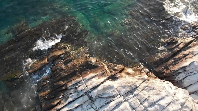 Aerial shot of waves crashing on sea rocks in slow motion