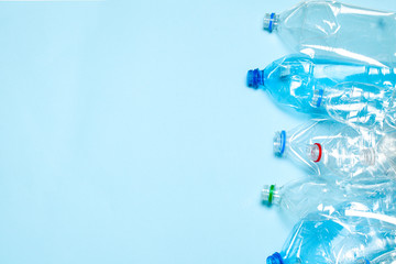 Crumpled plastic bottles on a blue background. Plastic trash. Copy space for text.