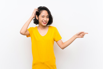 Asian young woman over isolated white background surprised and pointing finger to the side