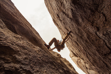 A rock climber pressing between two walls, between a rock and a hard place - obrazy, fototapety, plakaty
