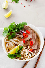 Vietnamese Pho Noodle Soup on light table. Beef with Chilli, Basil, Rice Noodles, Bean Shoots showing noodles