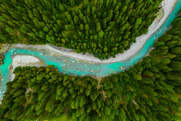 Inn River flowing in the forest in Switzerland. Aerial view from drone on a blue river in the...