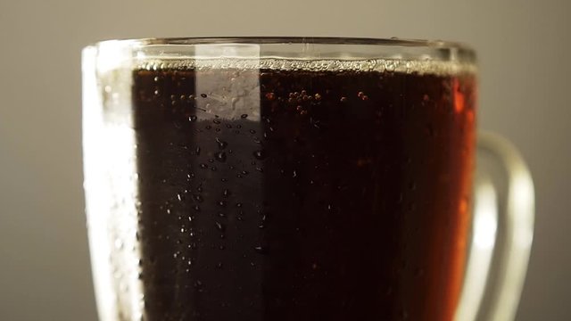 Glass full dark craft beer closeup rotate with drop of condensation cold drink