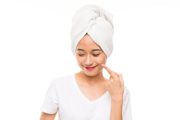 Asian young woman over isolated background with moisturizer
