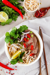 Vietnamese Pho Noodle Soup on light table. Beef with Chilli, Basil, Rice Noodles, Bean Shoots showing noodles