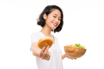 Asian young woman over isolated background with salad and donut © luismolinero