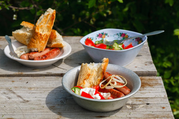 BBQ. Village lunch. grilled sausages with vegetable salad, onion and grilled bread.