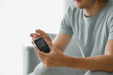 Diabetic man checking blood sugar level at home