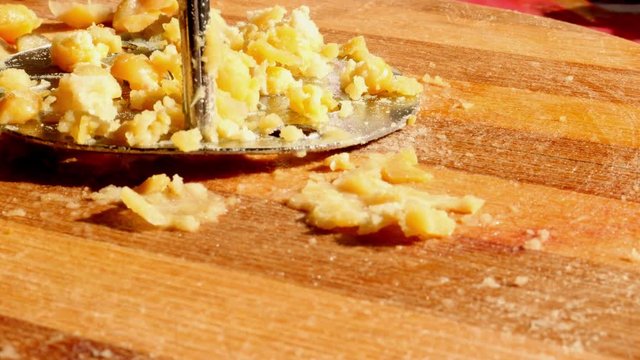 Smashing chickpea by masher. Cooking process. Wooden desk