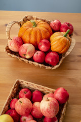 Fresh red apples and pumpkins in a basket on the table, which are very useful for a diet. Harvesting.