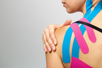 Kinesiotaping, kinesiology. Female athlete with kinesiotape, muscle tape on shoulder - obrazy, fototapety, plakaty