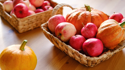 Fresh red apples and pumpkins in a basket on the table, which are very useful for a diet. Harvesting.