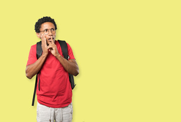 Serious young man asking for silence gesturing with his finger