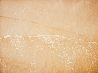 Naklejka premium Sand beach background, natural sea texture with little foam. Aerial top view