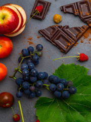 anticancer food, good for cardiovasculas system, fresh ripe grape, dark chocolate, raspberries, tomatoes, apple on concrete background. Food rich in resveratrol, antioxidants