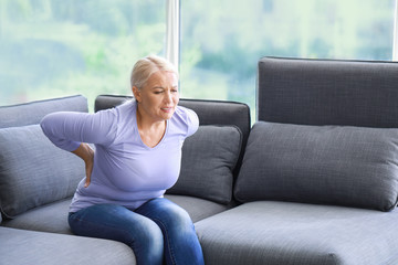 Obraz premium Mature woman suffering from back pain at home
