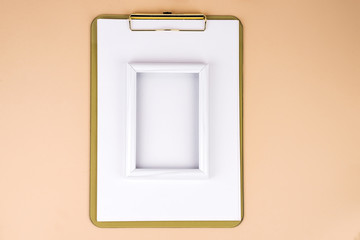 Clipboard with white frame on beige paper background, flat lay. Copy space