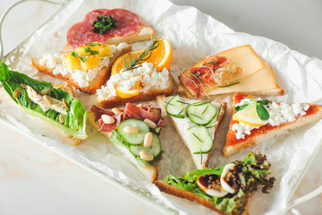 Tray with tasty sandwiches on light background