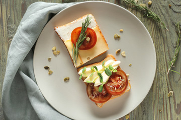 Plate with tasty sandwiches on wooden background