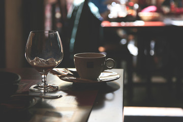 Cocktail glass and cup of coffee on table at a cafe