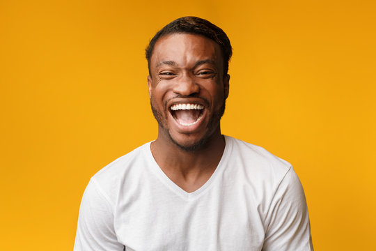 African American Man Laughing Looking At Camera Over Yellow Background