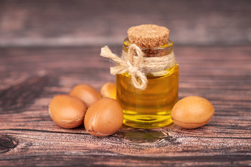 Argan oil, on wooden background. Argan nuts and seeds, for cosmetic and beauty products. Natural argan fruit from Morocco.