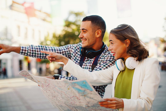 Young happy couple of tourists exploring the city with a map in hand