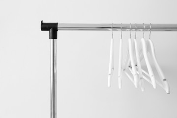 Rack with clothes hangers on light background