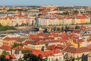 Obraz premium View over the roofs of Prague from the Mala Strana viewpoint with the Vltava river and roads, bridge and dancing house on the shore in sunny day and blue sky