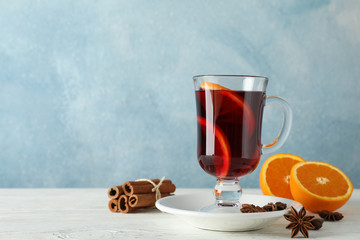 Mulled wine, orange and cinnamon on white wooden background, space for text