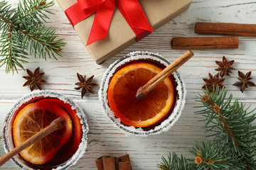 Glasses of tasty mulled and gift on white wooden background, top view