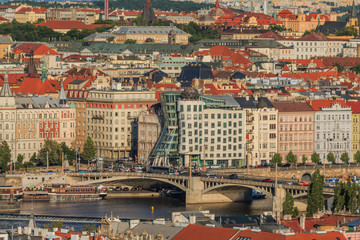 Fototapeta na wymiar View on historical buildings of Prague from the Mala Strana viewpoint with the river Vltava and streets, bridge, ships and dancing house on the shore in sunny day and blue sky