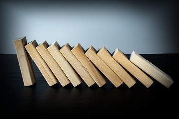 A wooden block stops the fall of other parts of the domino effect. Business risk management concepts.